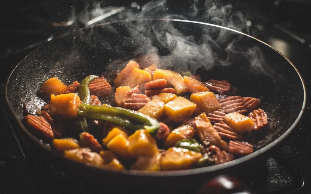 Healthy stir-fry with pumpkin, carrots, and green peppers in a steaming pan.