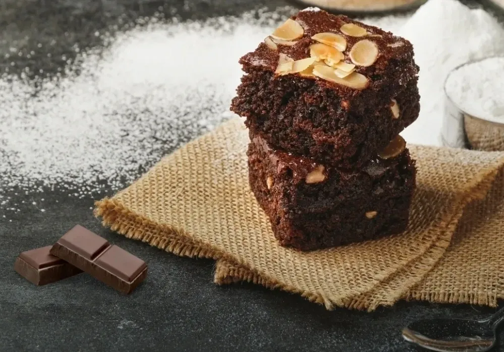 Sugar-free brownies recipe with almond slices on top, served on a rustic burlap cloth.