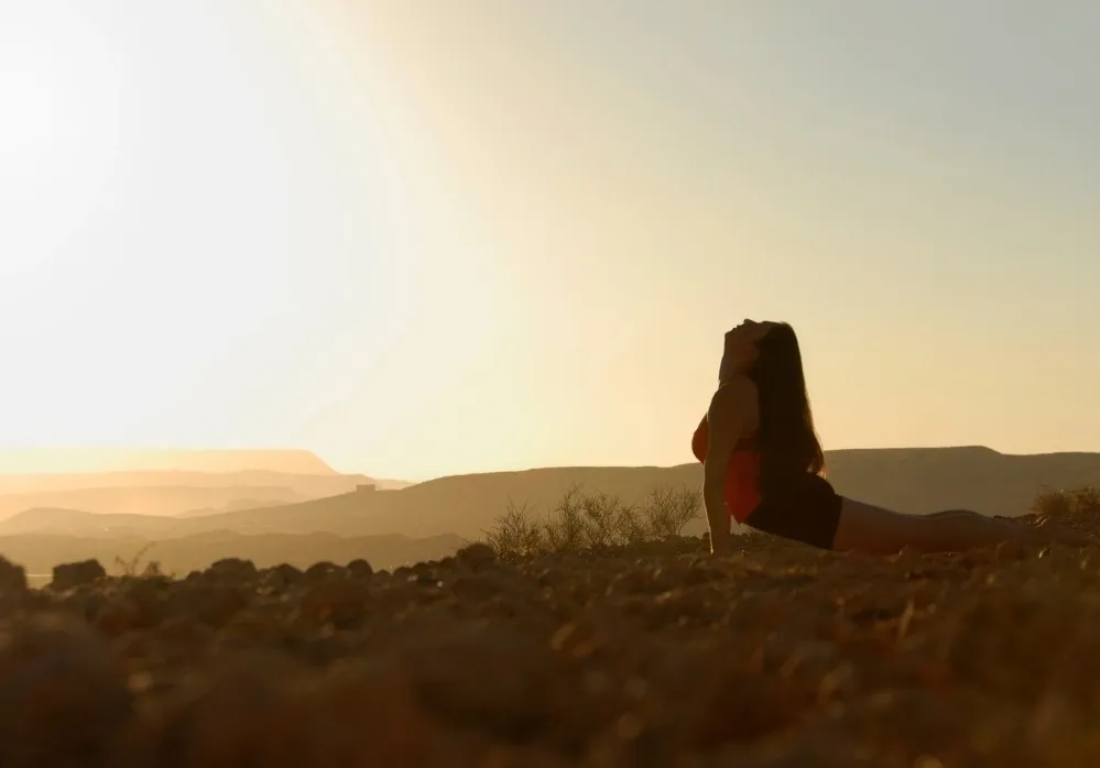 Woman practicing Cobra Pose ( Bhujangasana) outdoors at sunrise for yoga strength and flexibility.